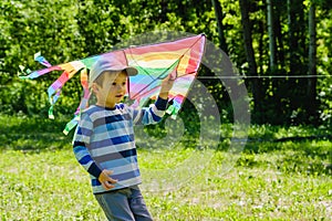 Happy child girl with a kite running on meadow in summer in nature