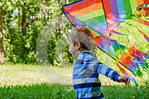 Happy child girl with a kite running on meadow in summer in nature