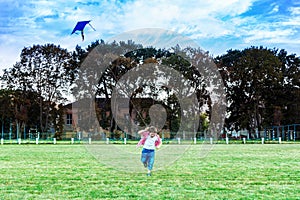 Happy child girl with a kite running on meadow in summer in nature