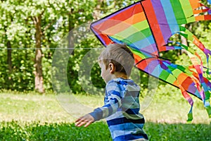 Happy child girl with a kite running on meadow in summer in nature