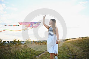 happy child girl with a kite running on meadow in summer in nature