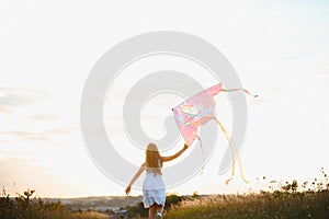 happy child girl with a kite running on meadow in summer in nature