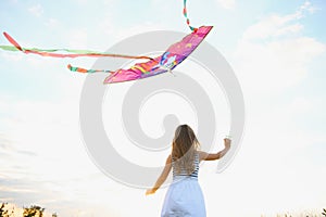 happy child girl with a kite running on meadow in summer in nature