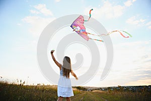 happy child girl with a kite running on meadow in summer in nature