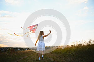 happy child girl with a kite running on meadow in summer in nature