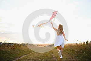 happy child girl with a kite running on meadow in summer in nature