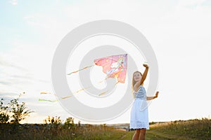 happy child girl with a kite running on meadow in summer in nature