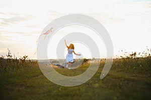 happy child girl with a kite running on meadow in summer in nature