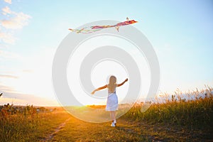 happy child girl with a kite running on meadow in summer in nature