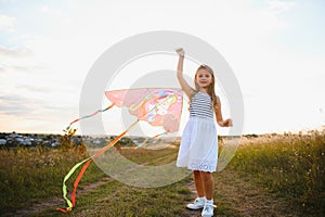 happy child girl with a kite running on meadow in summer in nature