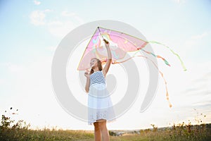 happy child girl with a kite running on meadow in summer in nature