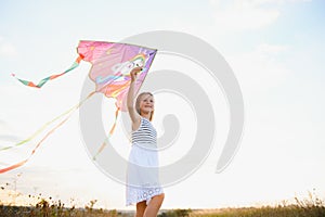 happy child girl with a kite running on meadow in summer in nature