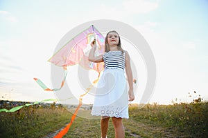 happy child girl with a kite running on meadow in summer in nature