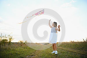 happy child girl with a kite running on meadow in summer in nature