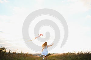 happy child girl with a kite running on meadow in summer in nature