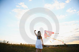 happy child girl with a kite running on meadow in summer in nature