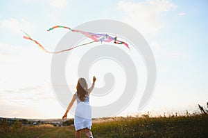 happy child girl with a kite running on meadow in summer in nature