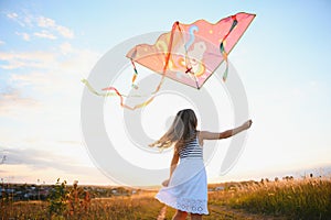 happy child girl with a kite running on meadow in summer in nature