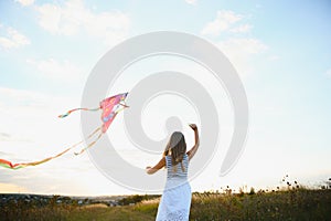 happy child girl with a kite running on meadow in summer in nature