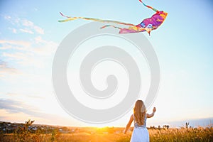 happy child girl with a kite running on meadow in summer in nature