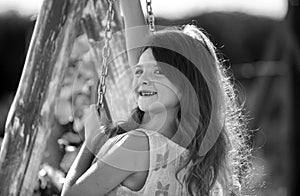 Happy child girl laughing and swinging on a swing at the park in summer. Kids happiness and smile. Child playing on