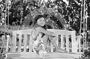 Happy child girl laughing and swinging on a swing at summer garden. Little girl having fun on a swing outdoor. Summer