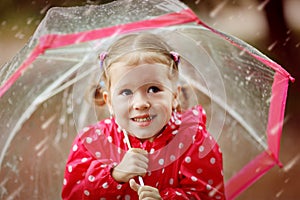 Happy child girl laughing with an umbrella in rain