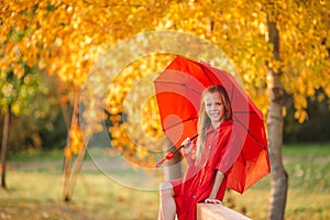 Happy child girl laughs under red umbrella