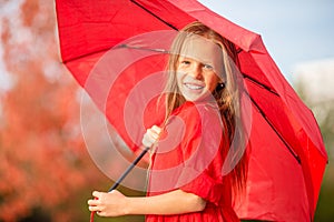 Happy child girl laughs under red umbrella