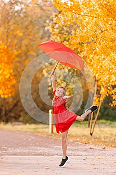 Happy child girl laughs under red umbrella