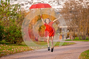 Happy child girl laughs under red umbrella