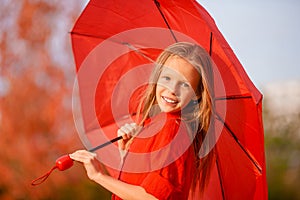 Happy child girl laughs under red umbrella