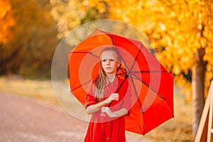 Happy child girl laughs under red umbrella