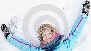 Happy child girl laying down on a frozen clear snow