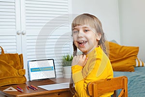 Happy child girl learning at home using tablet and having fun. Distance learning and on-line education concept