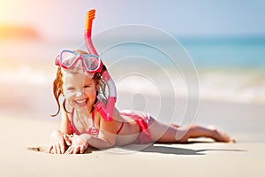 Happy child girl in a mask on the beach