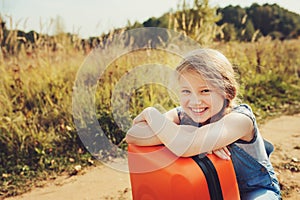 Happy child girl with orange suitcase traveling alone on summer vacation. Kid going to summer camp.