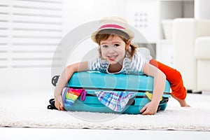 happy child girl packs clothes into suitcase for travel, vacation