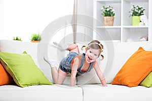 Happy child girl playing on couch at home