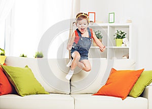 Happy child girl playing and jumping on couch at home