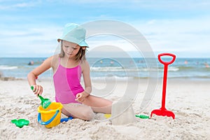 Happy child girl playing with sand at the beach in summer