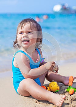 Happy child girl playing with sand and toys at the beach