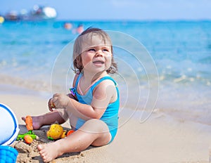 Happy child girl playing with sand and toys at the beach