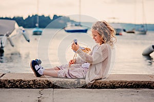 Happy child girl playing with toy bird on summer seacoast