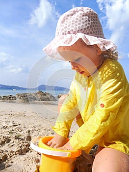 Happy child girl playing with toys on the beach. Summer vacation