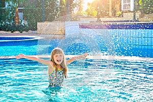 Happy child girl playing in the water and splashes water drop swimming pool. Summer vacation concept