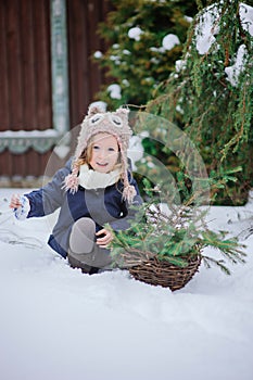 Happy child girl plays in winter snowy garden