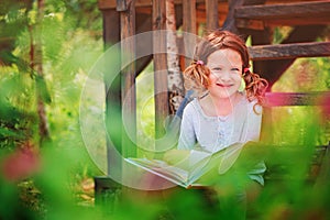 Happy child girl reading book outdoor