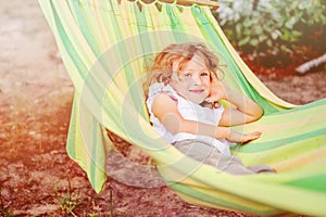 Happy child girl relaxing in hammock in summer