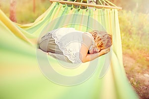 Happy child girl relaxing in hammock in summer forest